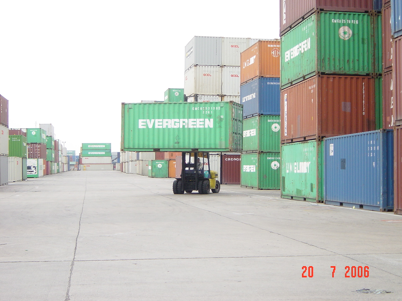 A forklift carries a shipping container through a container yard, photographed in 2006